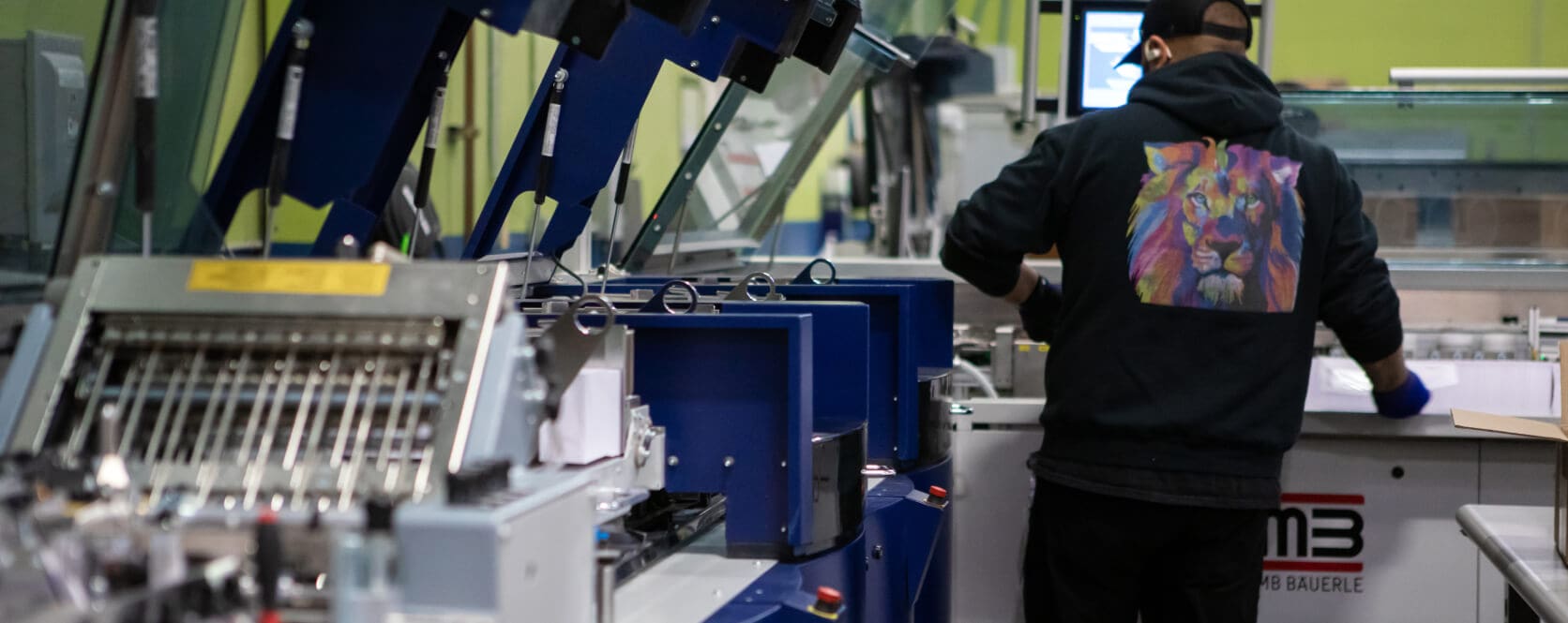 A person operates printing machinery in a production environment