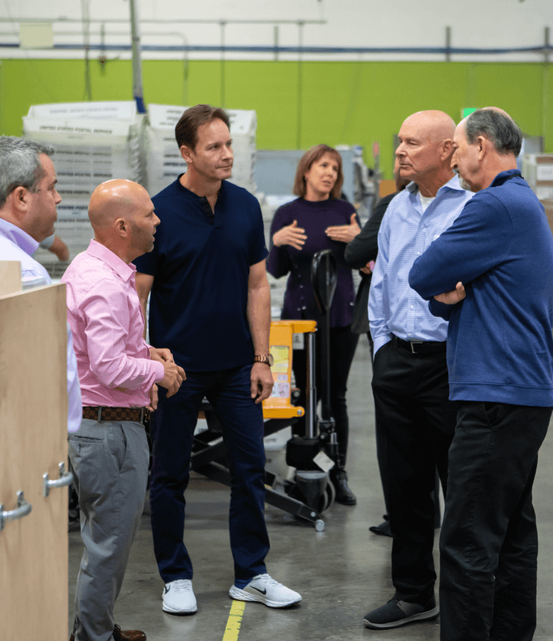 group action shot with 5 men talking in a warehouse