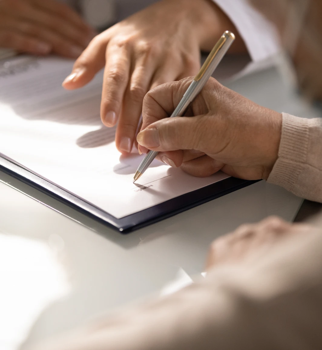 close up shot of a hand holding a black pen signing a legal document