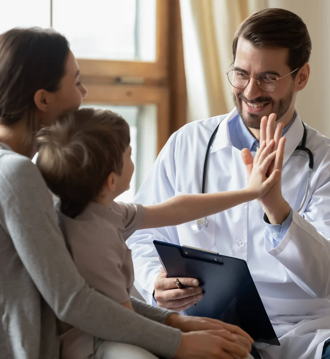 Mother holding her son as he gives a high five to a doctor