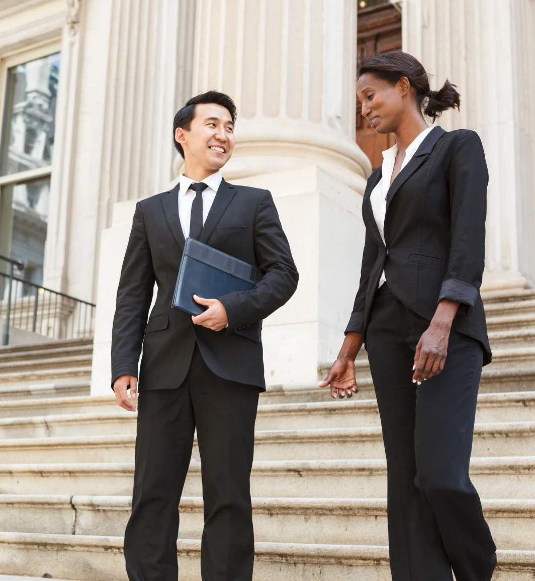 Two people in suits conversing on the steps in front of a government building