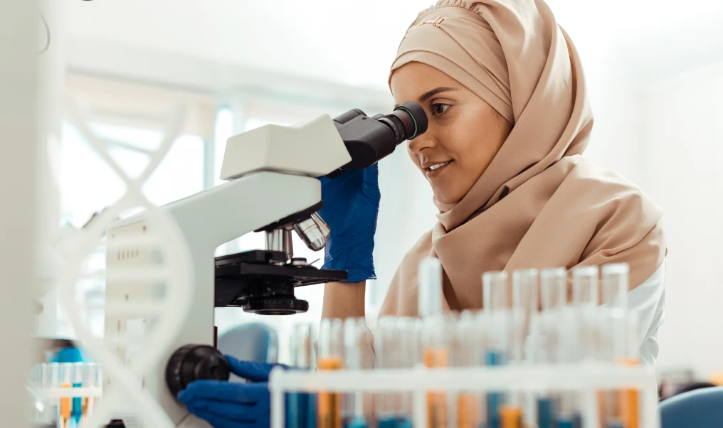 A person looking through a microscope in a lab environment