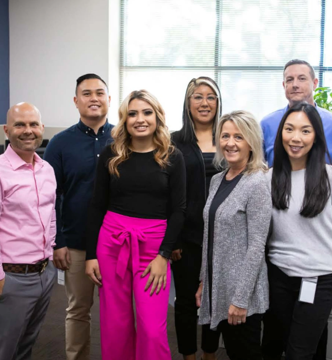 group photo with seven individuals in business professional attire in an office