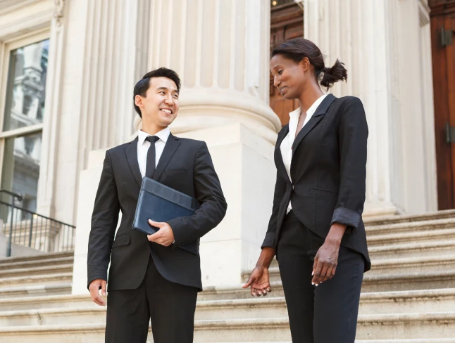 Two people in suits conversing on the steps in front of a government building