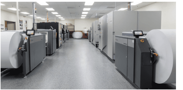 grey office building walkway with large paper rolls used for large scale printing projects on the left and right of the aisle